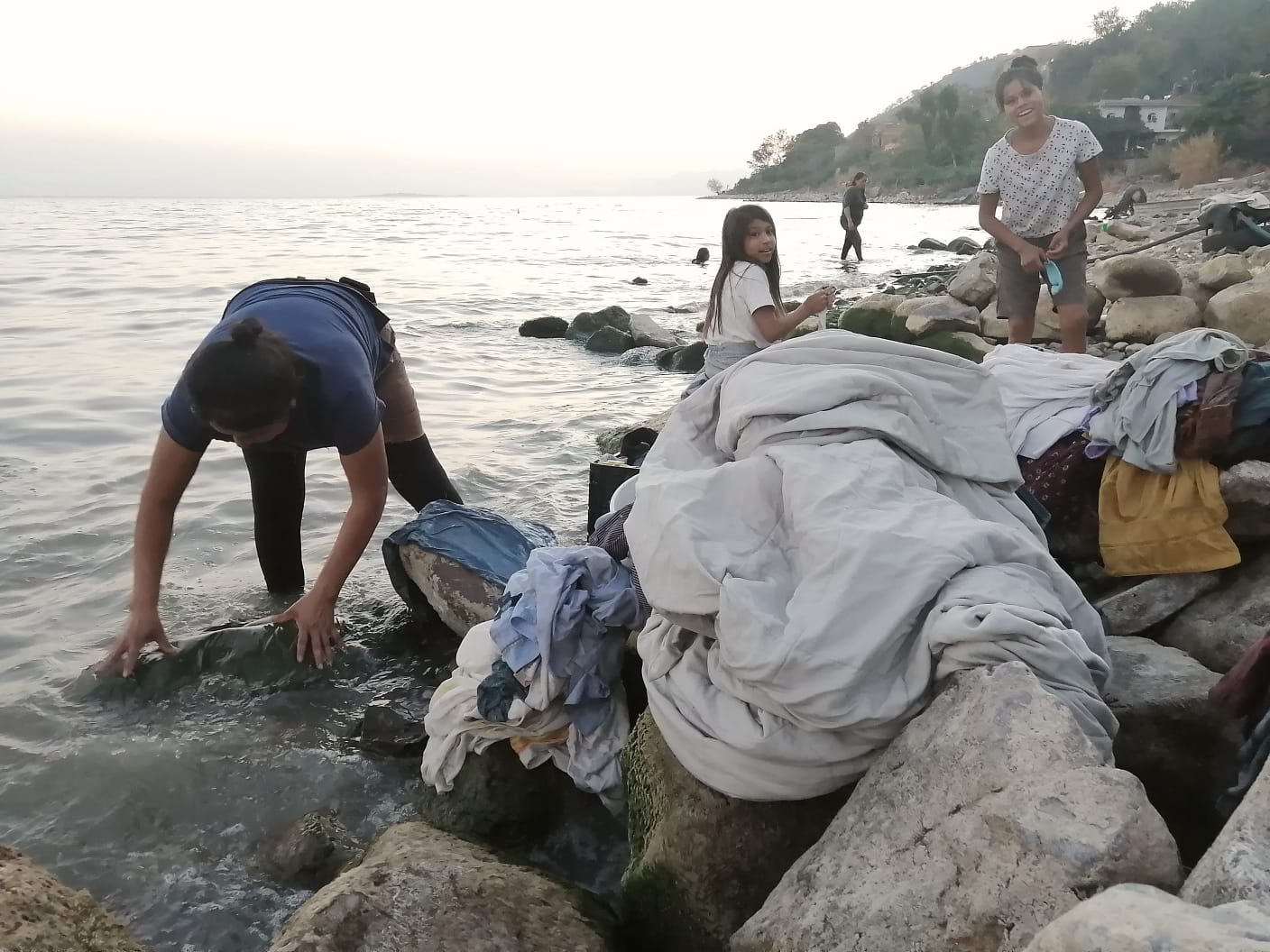 Un grupo de personas en una playa junto a una roca Descripción generada automáticamente con confianza media